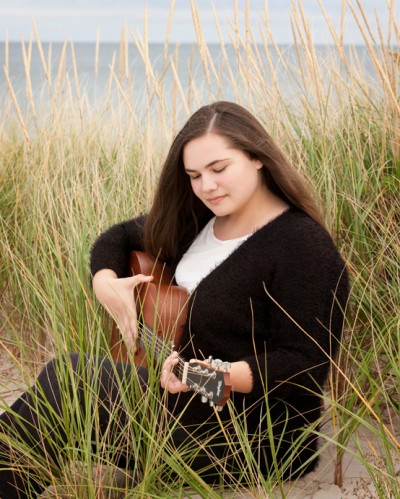 Girl in grass playing guitar