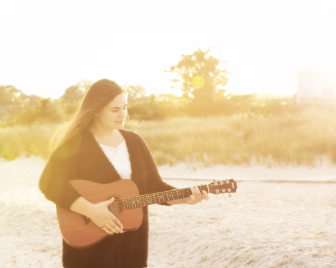girl playing guitar with sun flare