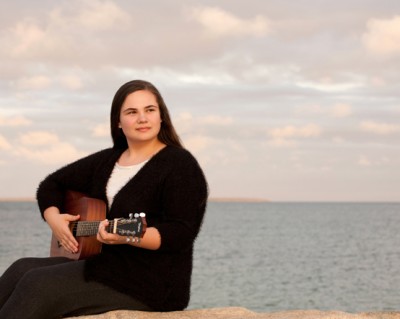 Girl by ocean playing guitar