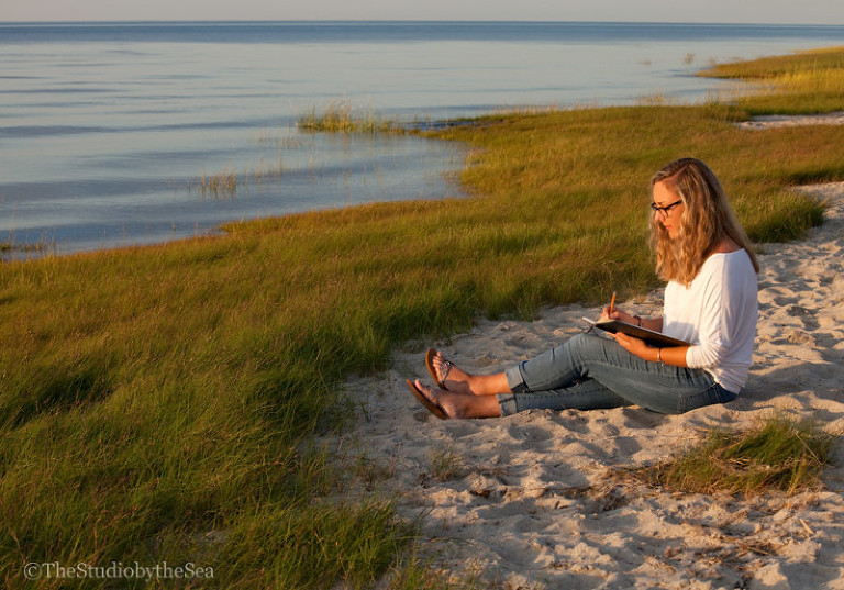 Teen drawing on beach at sunset