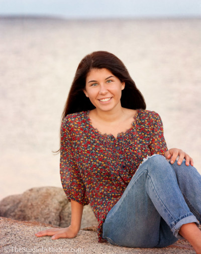 Teen sitting on jetty with beach behind her