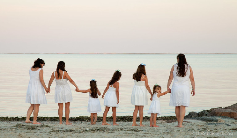 girls holding hands looking out over ocean
