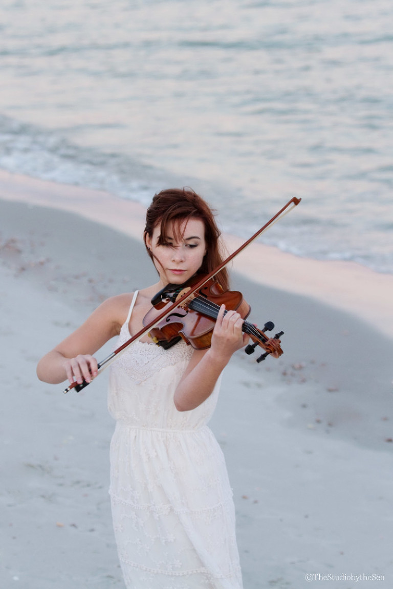 Senior girl playing violin by the sea