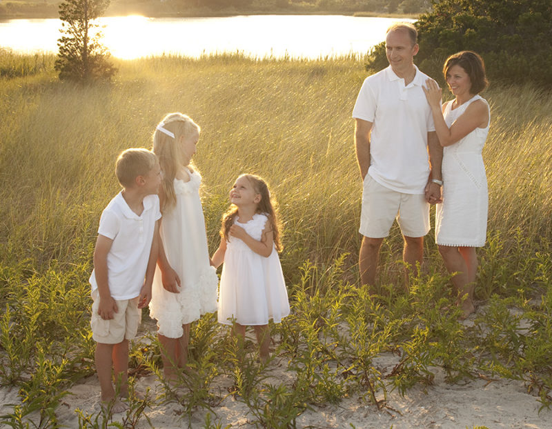 mom and dad with three small children in the beach grass at the golden hour