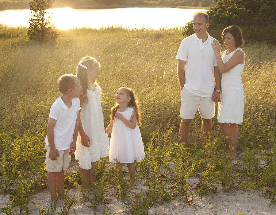 mom and dad with three small children in the beach grass at the golden hour