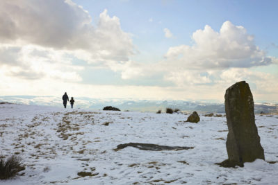 dad and daughter walking on snowy day near standing stones