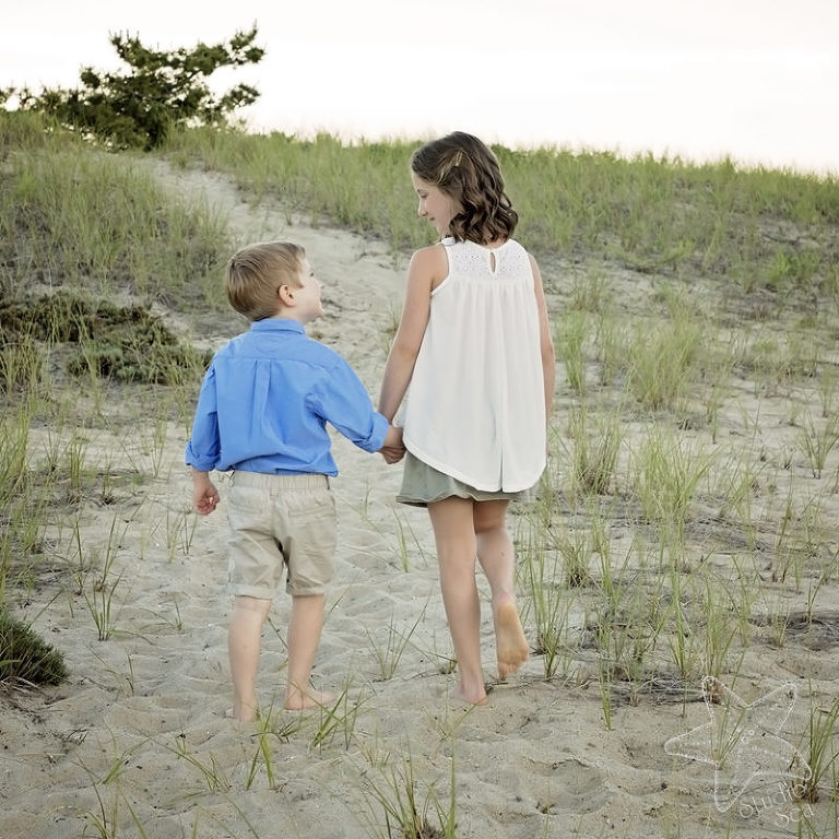 Image from back of two children walking on sand dunes