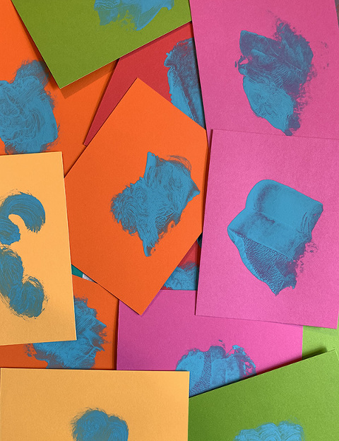 brightly coloured cards with smears of blue paint on them