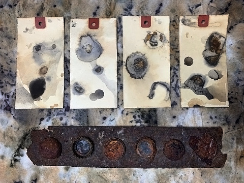tags that have been rust printed along side rusted metal objects